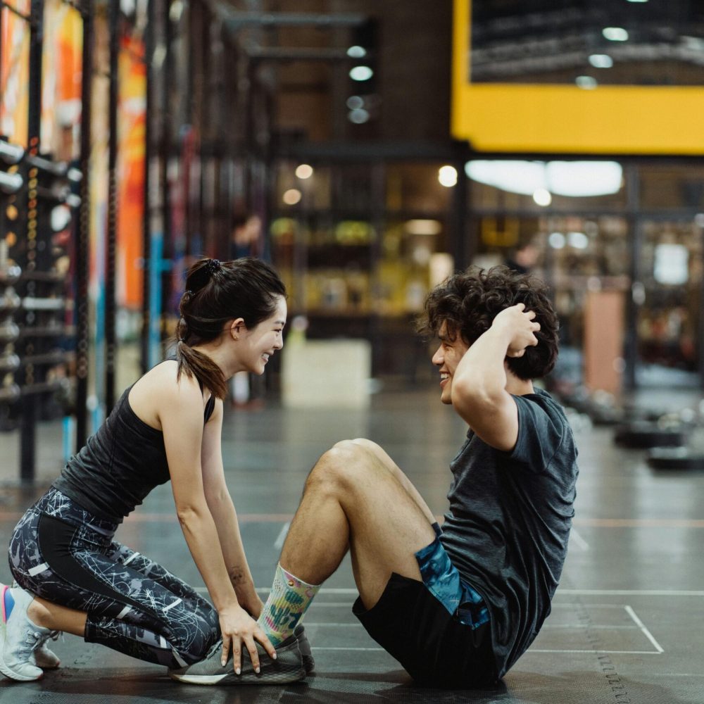 Asian couple enjoys fitness routine together in a gym, promoting healthy lifestyle and partnership.